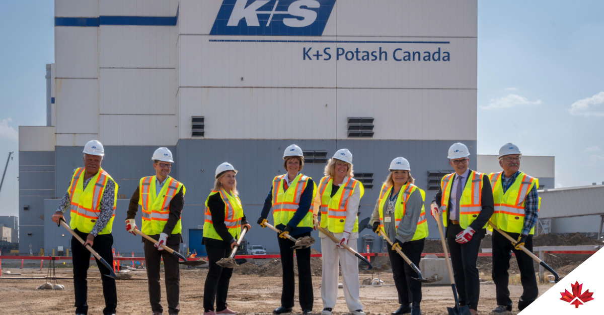 Huit personnes en tenue de sécurité tiennent des pelles devant un bâtiment portant l'enseigne "K+S Potash Canada", lors d'une cérémonie de première pierre. Laurel Broten, PDG d’Investir au Canada, est au centre, la cinquième personne à partir de la gauche.