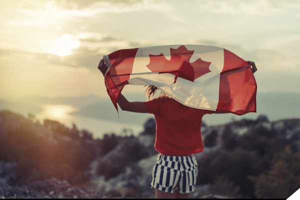 Woman holding Canadian flag in front of mountain landscape