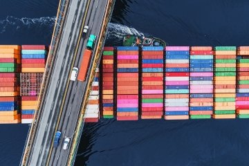 Un navire porte-conteneurs passe sous un pont suspendu.