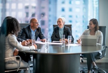 Équipe d’affaires en réunion dans une salle de conseil, collaborant autour d’une grande table dans un bureau moderne.