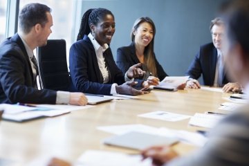 Femme professionnelle afro-américaine dirigeant une discussion d’affaires avec des collègues dans un bureau moderne.