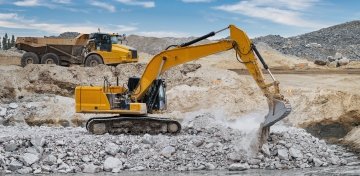 Une excavatrice et un tombereau travaillant sur un remblai de pierres.