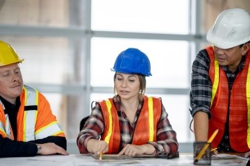 Une contremaîtresse portant un équipement de sécurité tient un bloc-notes et regarde vers le haut alors qu'elle se tient debout sur un site minier.