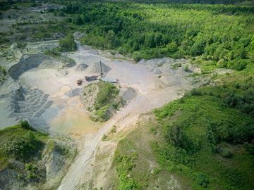 Vue aérienne d'une mine à ciel ouvert entourée d'arbres verdoyants.