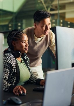 Ingénieurs logiciels collaborant et analysant du code sur plusieurs écrans d’ordinateur dans un environnement de bureau.