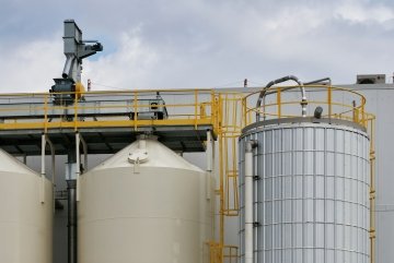 Vue rapprochée au niveau de la rue de silos de stockage industriels avec échelles et tuyaux métalliques jaunes, photographiés à Saskatoon, Canada.