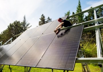 Installateur solaire assemblant une structure de panneaux solaires au sol.