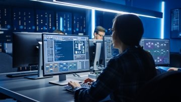 Professionnelle des TI travaillant à un poste informatique dans une salle de contrôle d’un centre de données.