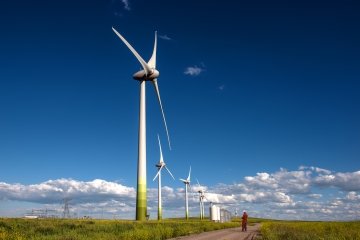 Grandes éoliennes illustrant une comparaison d’échelle avec un technicien au sol.