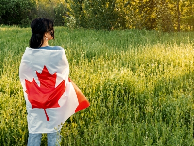 woman wrapped in Canadian flag standing in field